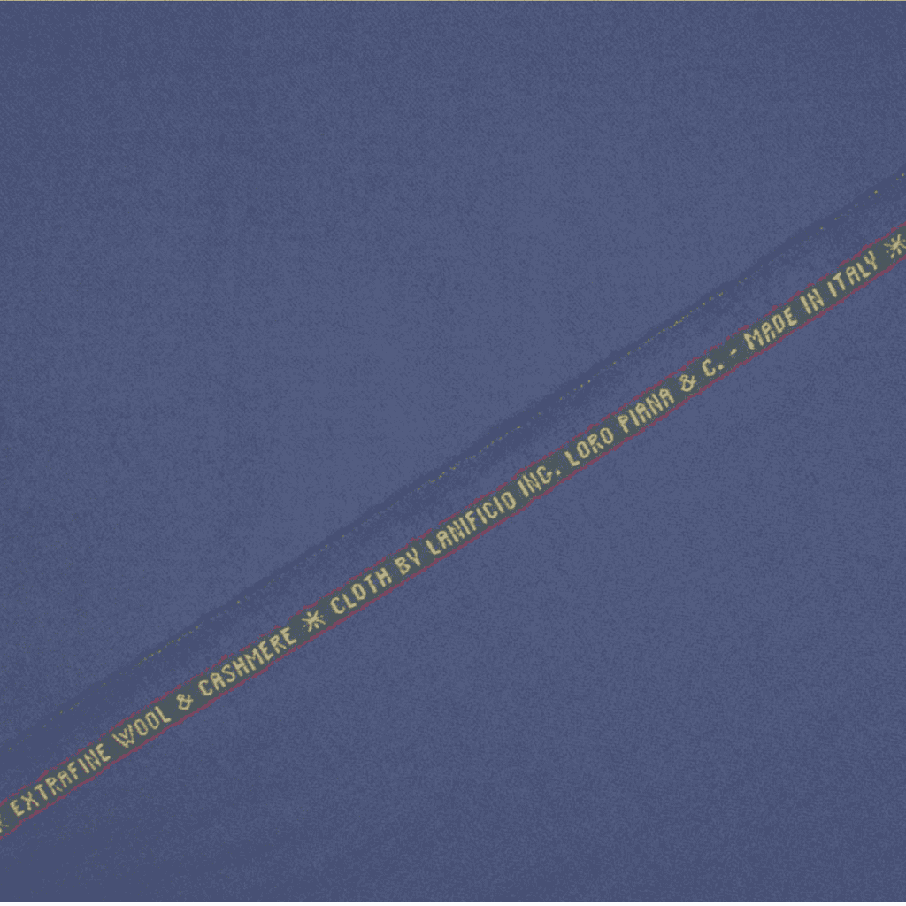 A swatch of periwinkle blue Loro Piana wool & cashmere superfine suitiing fabric with the brand name and content information printed on the fabric.