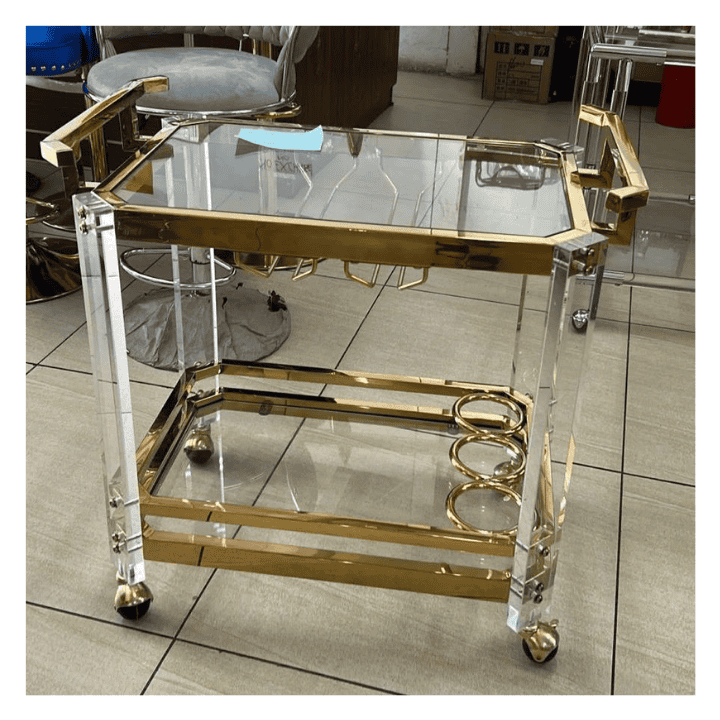 Gold-colored two-tier dining cart with acrylic top and steel frame, featuring gold handles and caster wheels.