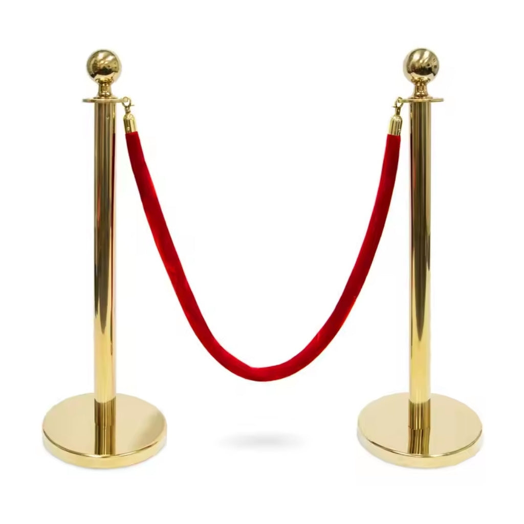 Gold stanchions with a red velvet rope on a white background